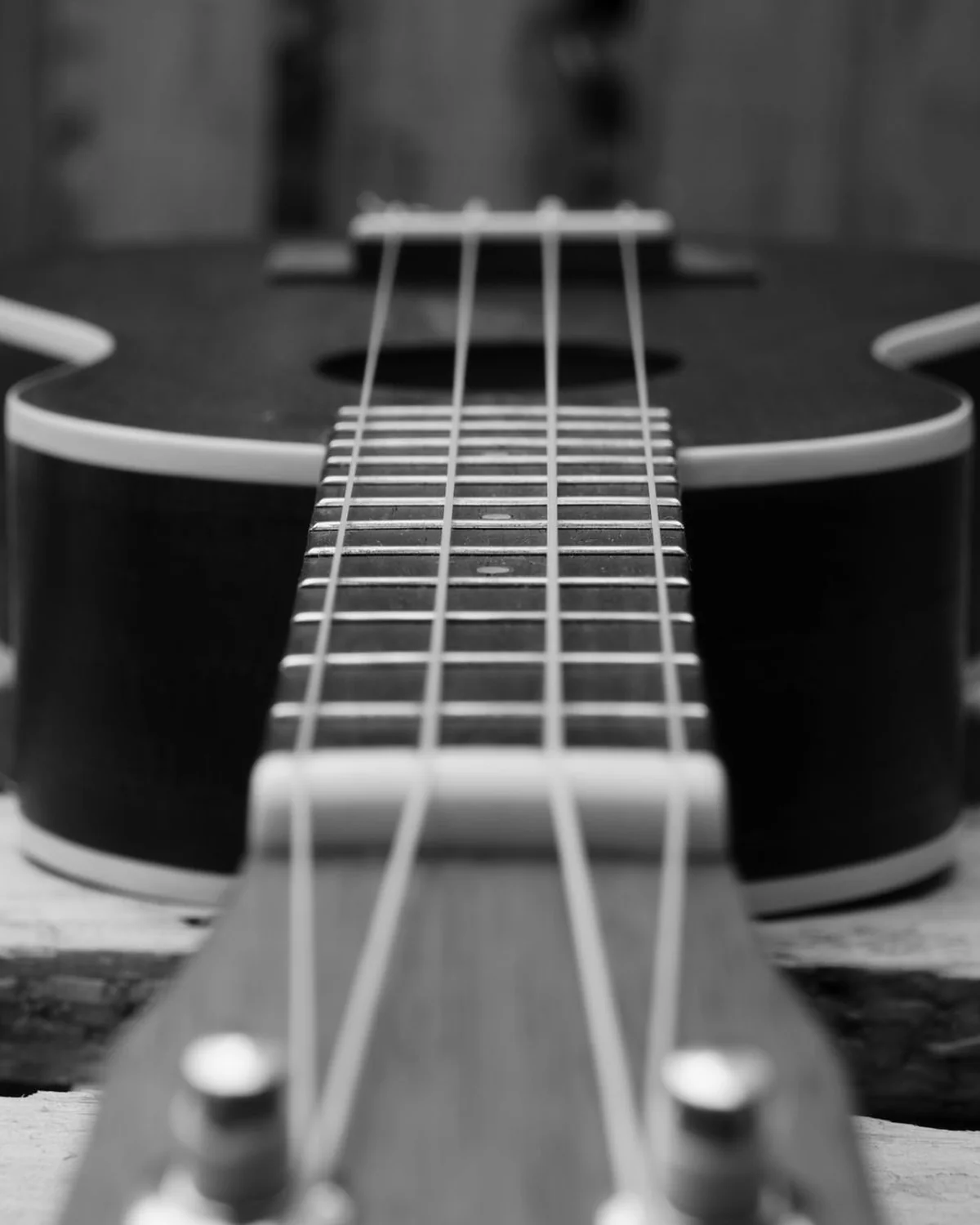 Close-up black and white photo of a ukulele body and strings